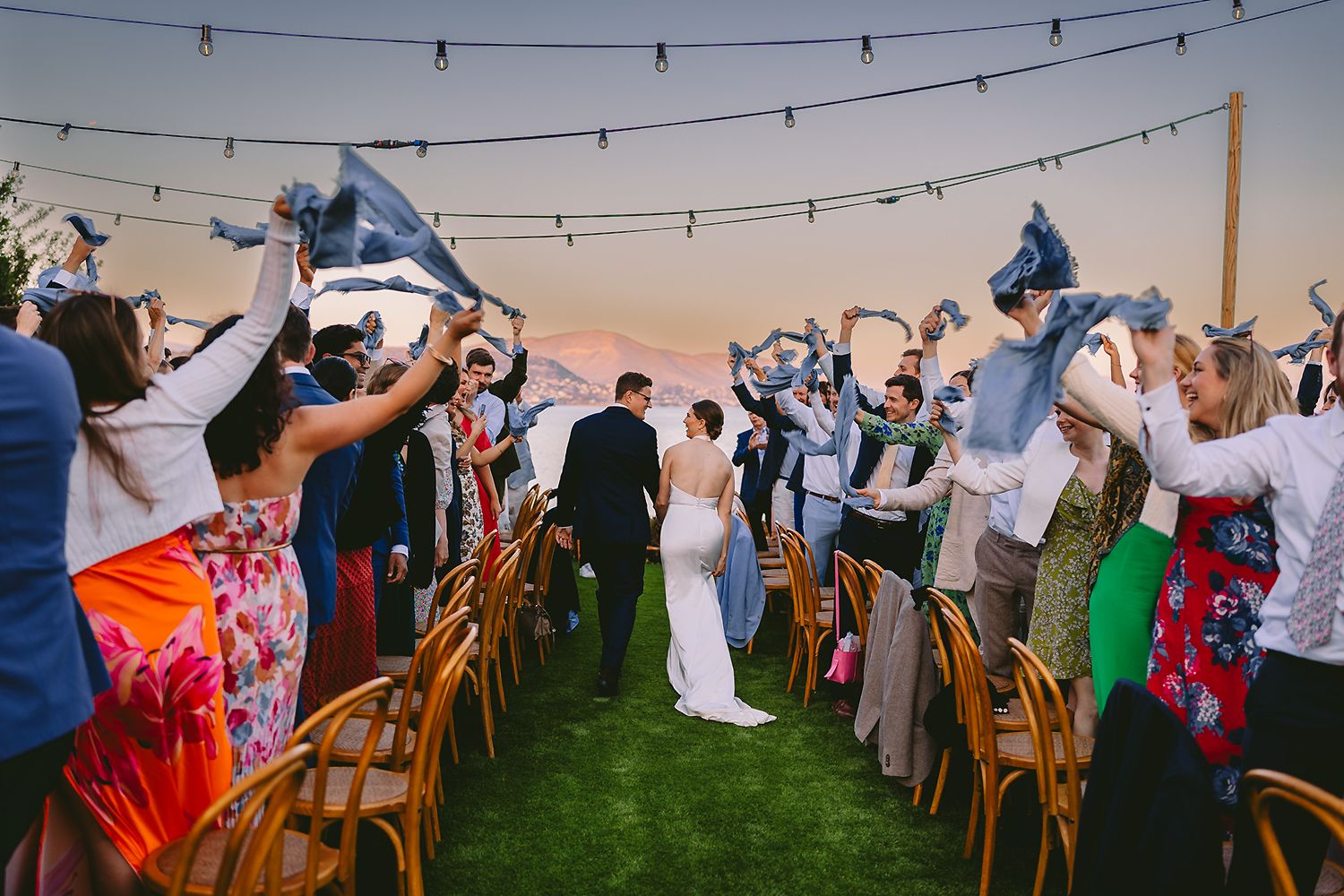 Wedding photography in Athens Riviera sunset with couple and guests celebrating, destination wedding Greece.Photo Georgenafpliotis.com