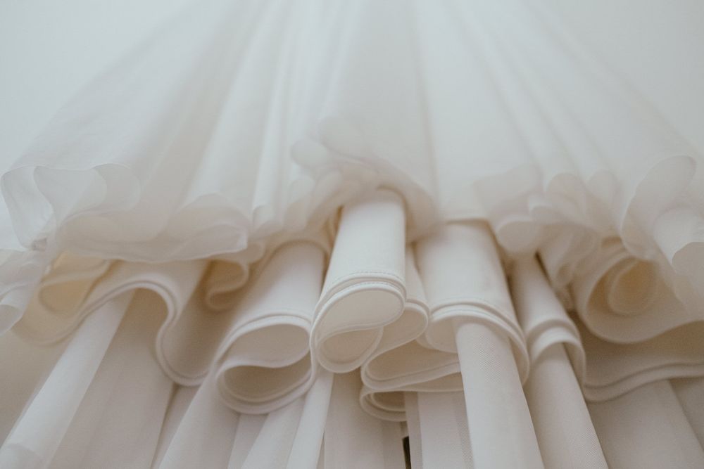 Close-up of layered white tulle and fabric ruffles on a bridal ball gown skirt.