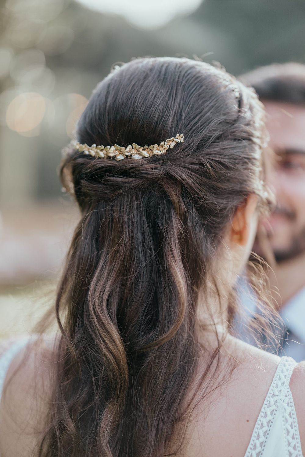 Bride with dark hair in elegant half-up style adorned with a delicate gold leaf hair vine accessory.