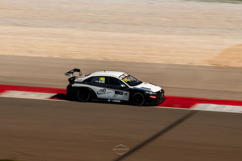 White race car competing on a sandy desert racing circuit during a professional motorsport championship event.