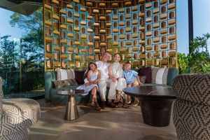 Family of four posing together on a stylish outdoor lounge with decorative geometric wall backdrop at a luxury resort.