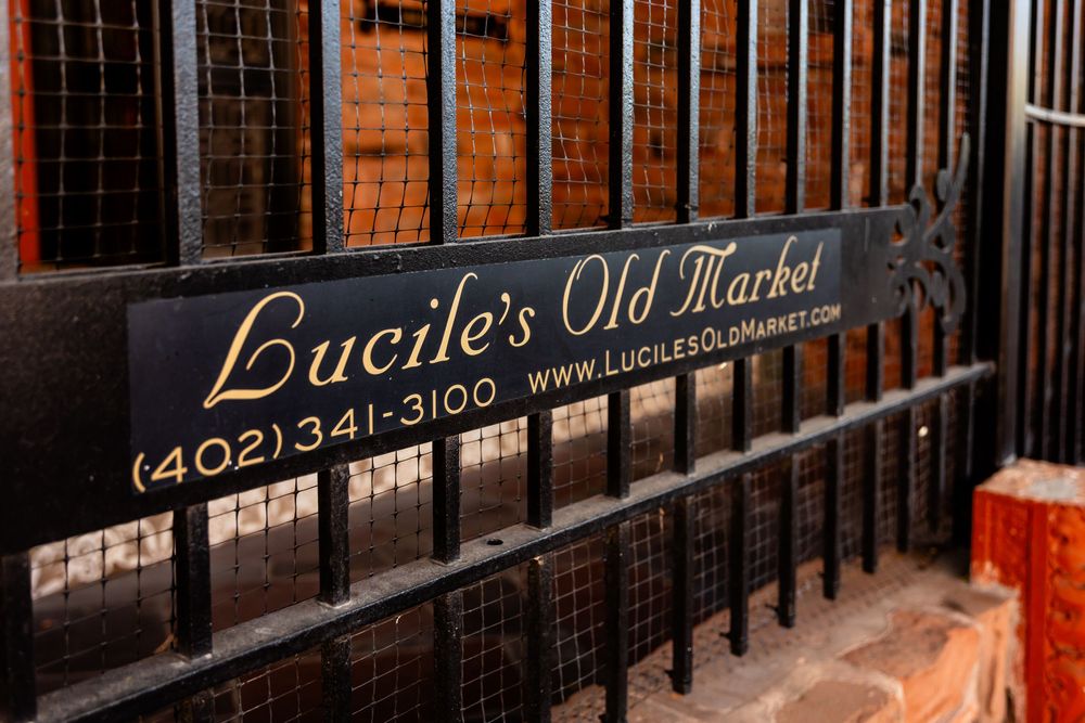 Lucile's Old Market restaurant sign with phone number and website on decorative black iron gate in Omaha, Nebraska.