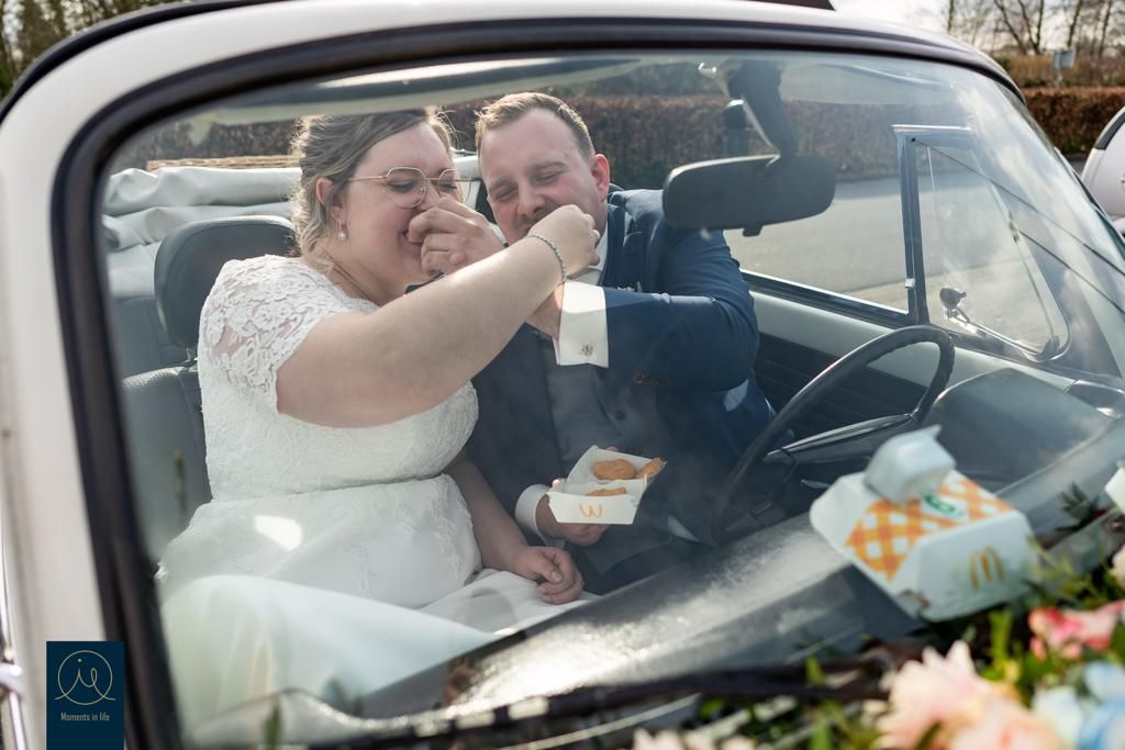 Bruid en bruidegom delen een vreugdevol moment in een oldtimer op hun trouwdag.