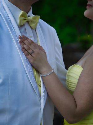 Close-up of prom couple showing yellow bow tie, white tuxedo vest, and yellow formal dress detail.