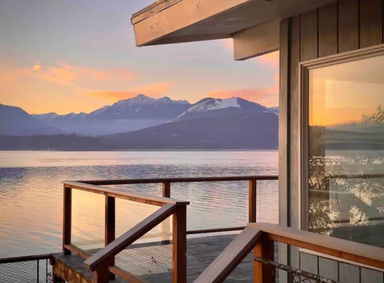 Back porch of a rental home that overlooks a large lake with mountains behind in Seabeck Washington