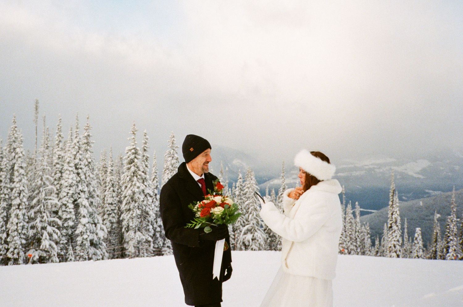 35 mm film photo of bride reading her vows on a snowy ski hill in Revelstoke