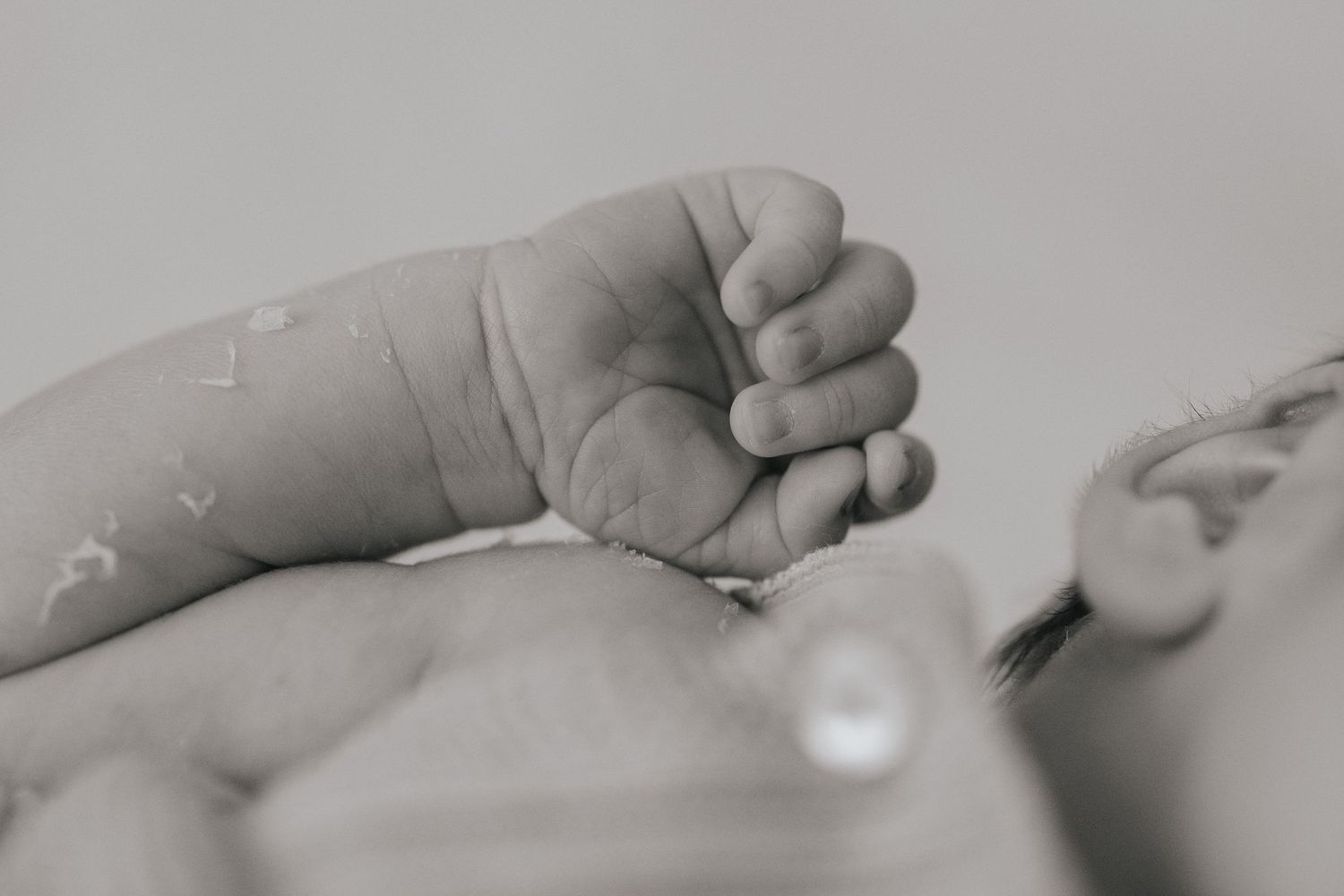 Close-up of tiny newborn baby feet resting on a soft white blanket held by a parent.