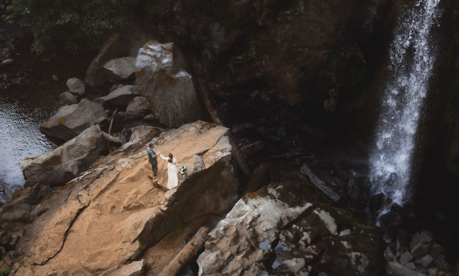 Couple in wedding attire embracing on a misty Oregon coast beach with dramatic sea stacks in the background.