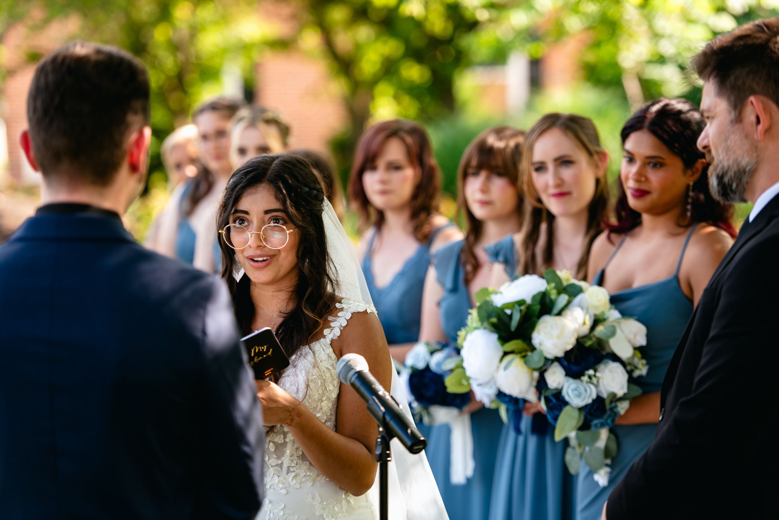 Bride and groom share first kiss on wooden deck overlooking lush green landscape at outdoor wedding ceremony.