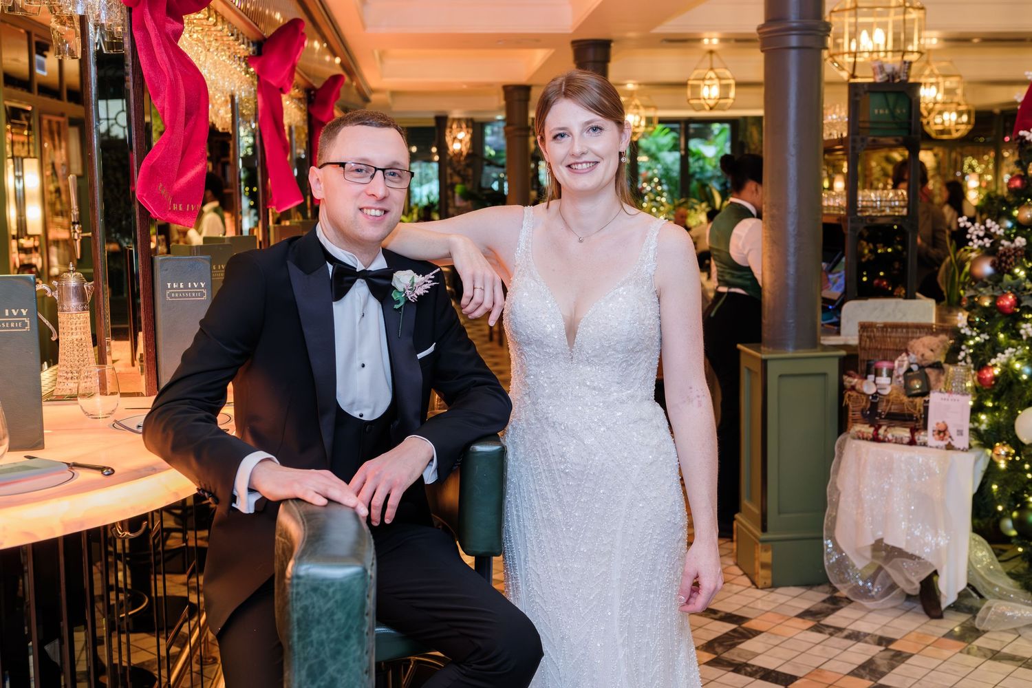 Bride and groom posing together in an elegant restaurant wedding venue decorated with Christmas trees and warm lighting.