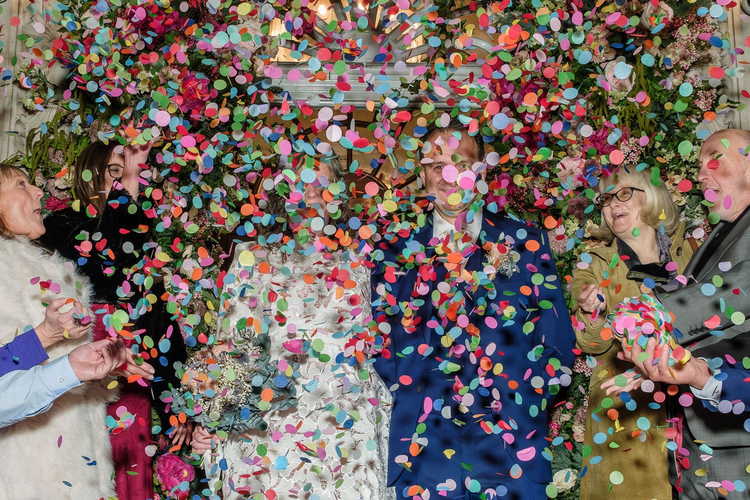 Group of people celebrating with colorful confetti flying through the air at a festive party event.