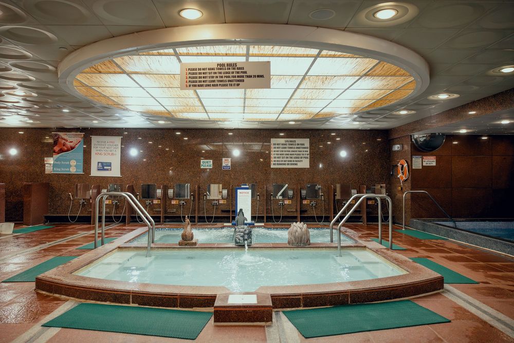 Indoor spa pool with jacuzzi jets, green tile accents, and elegant ceiling lighting in a luxury wellness center.