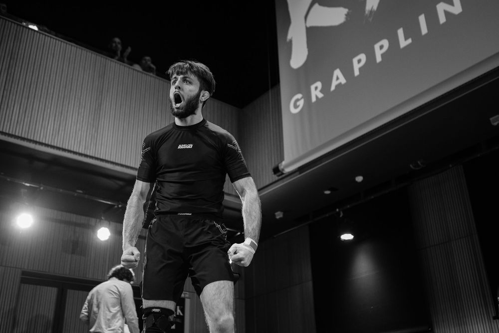 Fighter celebrating victory at grappling competition in black and white photo.