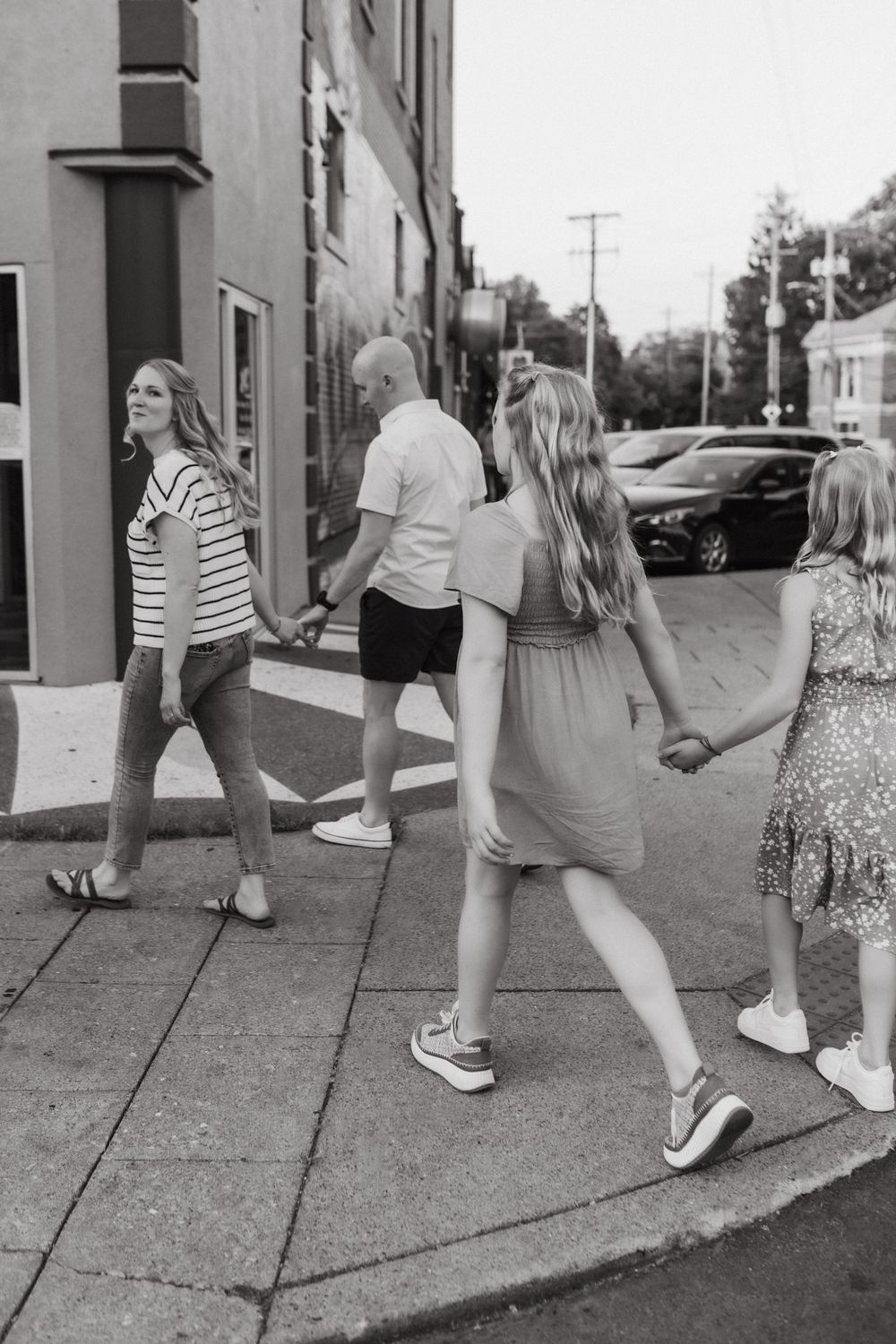 Black and white photo of a family holding hands while walking together on a city sidewalk in Louisville, KY.