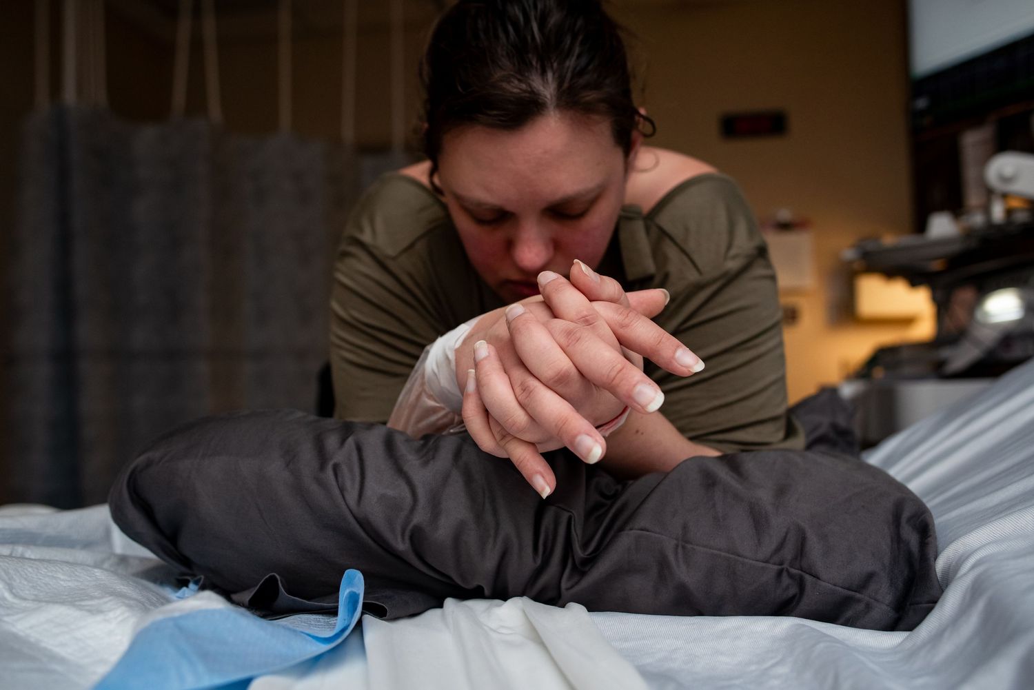 Woman in labor clasps her hands and leans over the bed at Bryan Hospital in Lincoln NE