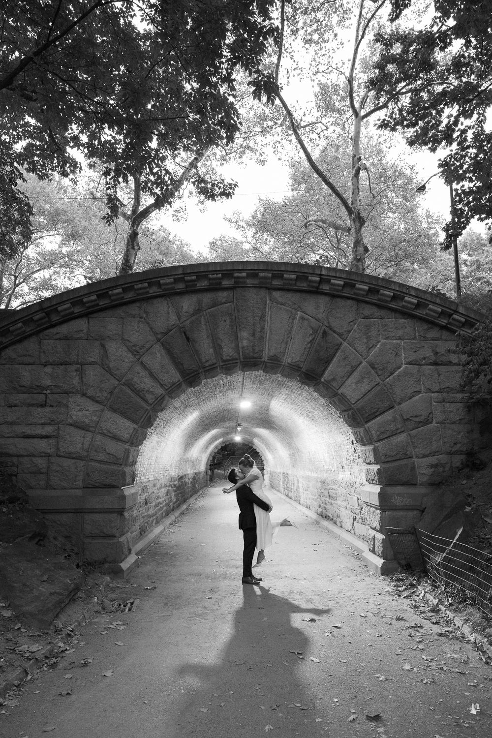 Black and white photo of a couple dancing under an arched stone tunnel in Central Park.