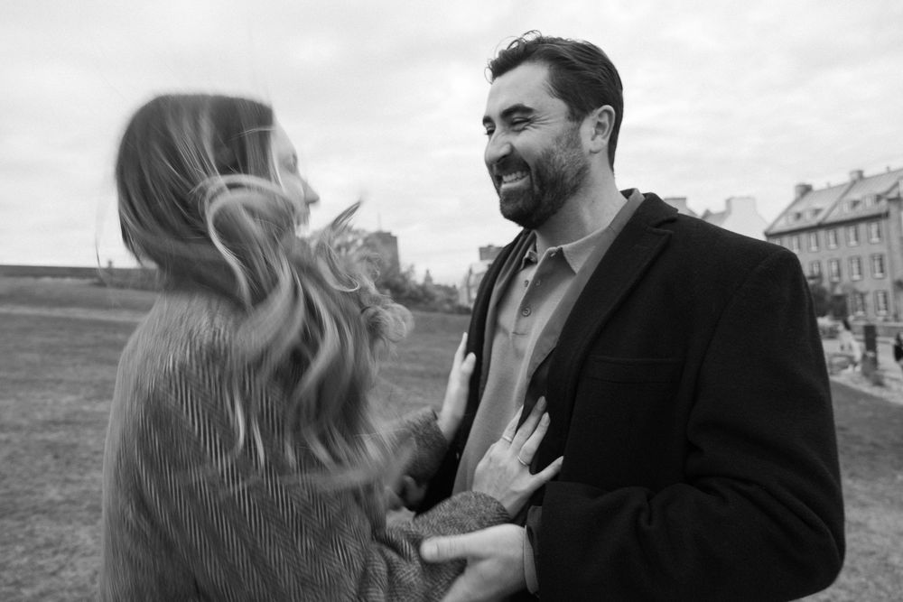 Laughing couple sharing a joyful moment together in a black and white outdoor photo.