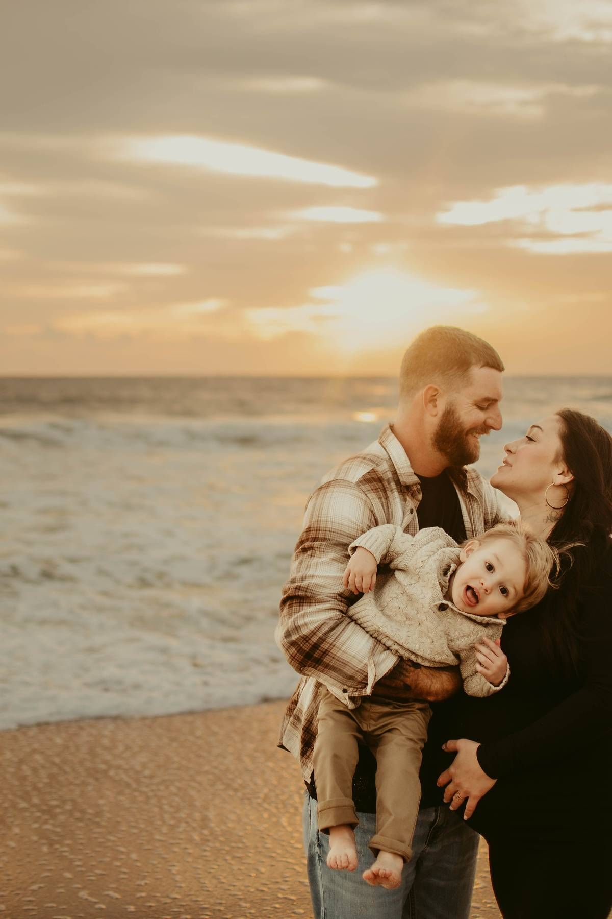 Family sharing joyful moments together on a beach during golden hour.