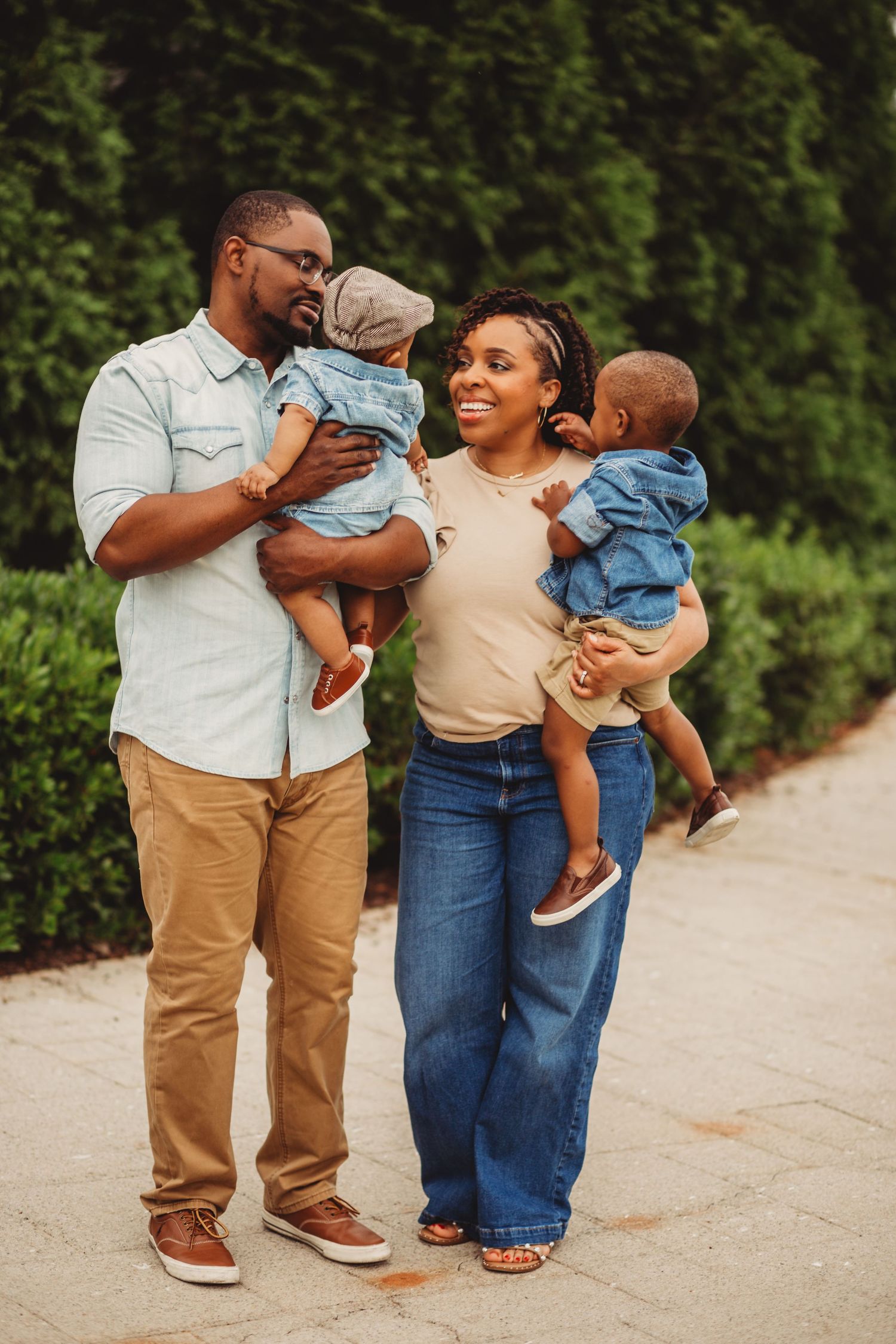 Family with two young sons smiles at each other in the park