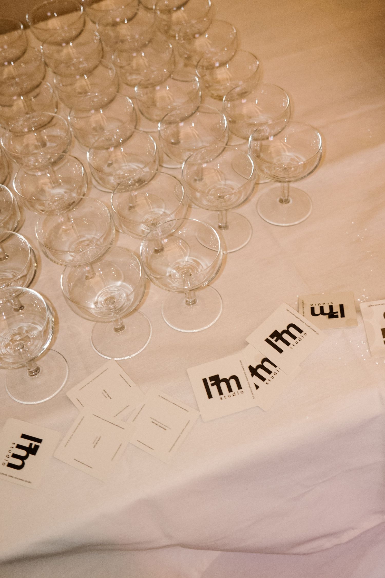 Array of empty wine glasses arranged on white tablecloth with decorative paper elements.