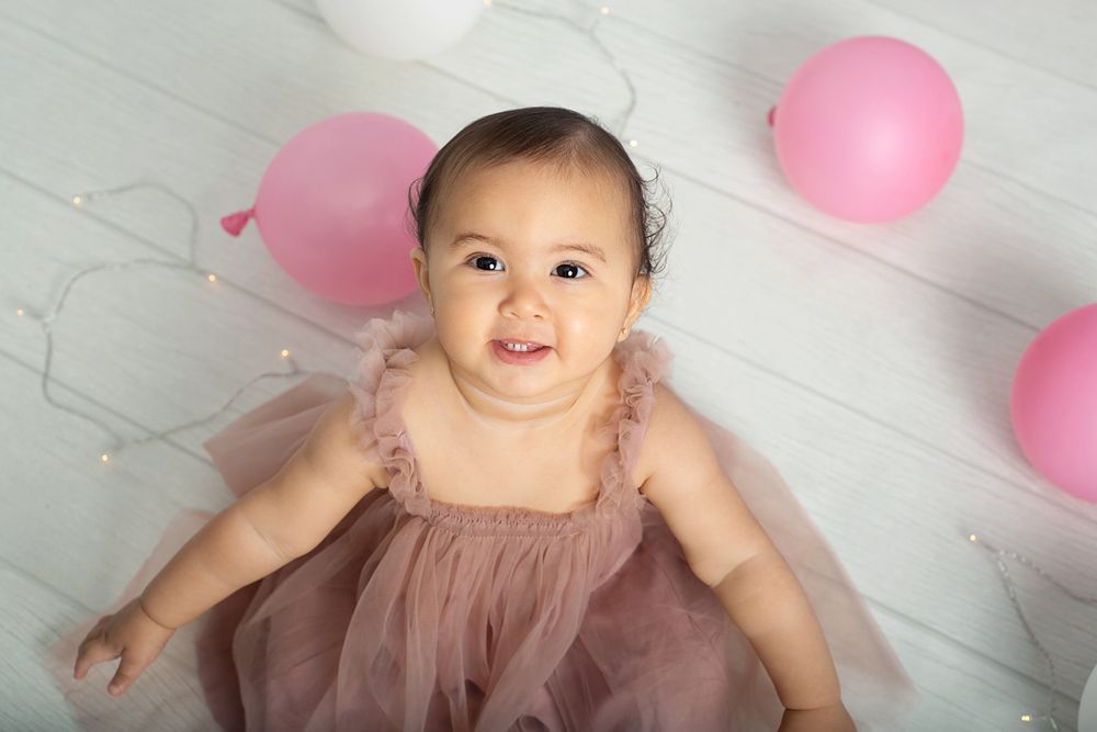 one year old girl sits wearing pink tulle dress for first birthday session in Baltimore Ontario*