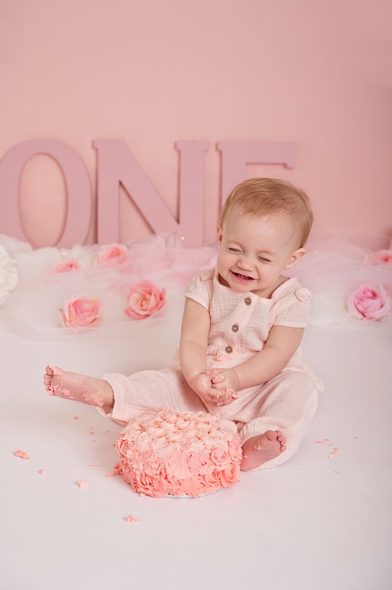 laughing baby girl in pink romper, first birthday cake smash session with pink ombré cake and pastel decorations, Baltimore, Ontario*