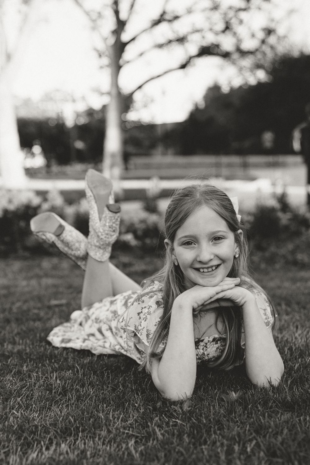 Black and white photos of someone lying on grass in a floral dress.