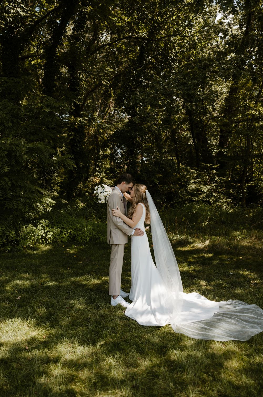 A bride and groom embrace in a lush, verdant forest setting on their wedding day. Fort Worth Texas wedding photographer.