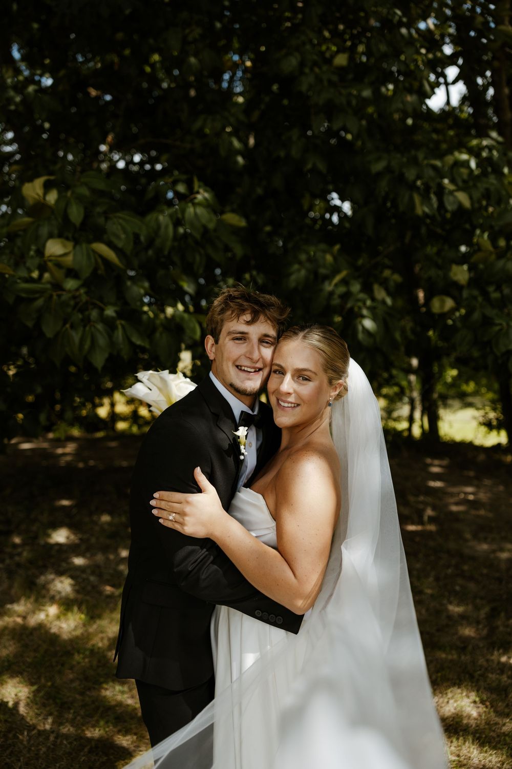A bride and groom embrace in a lush, wooded setting on their wedding day. Fort Worth Texas wedding photographer.