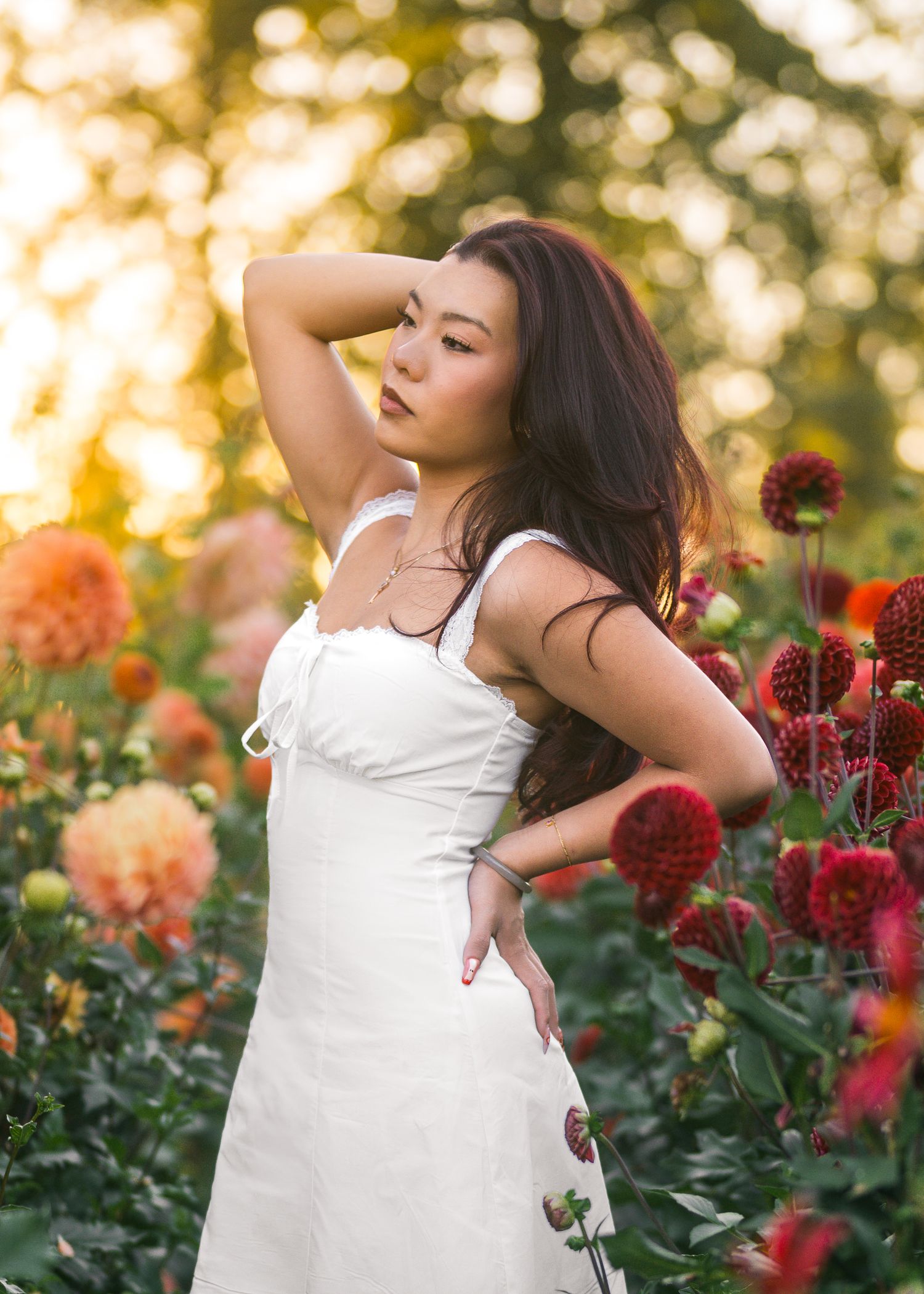 Asian girl posing in a row of flowers at wild hearts farms in Tacoma, WA for her senior photos.