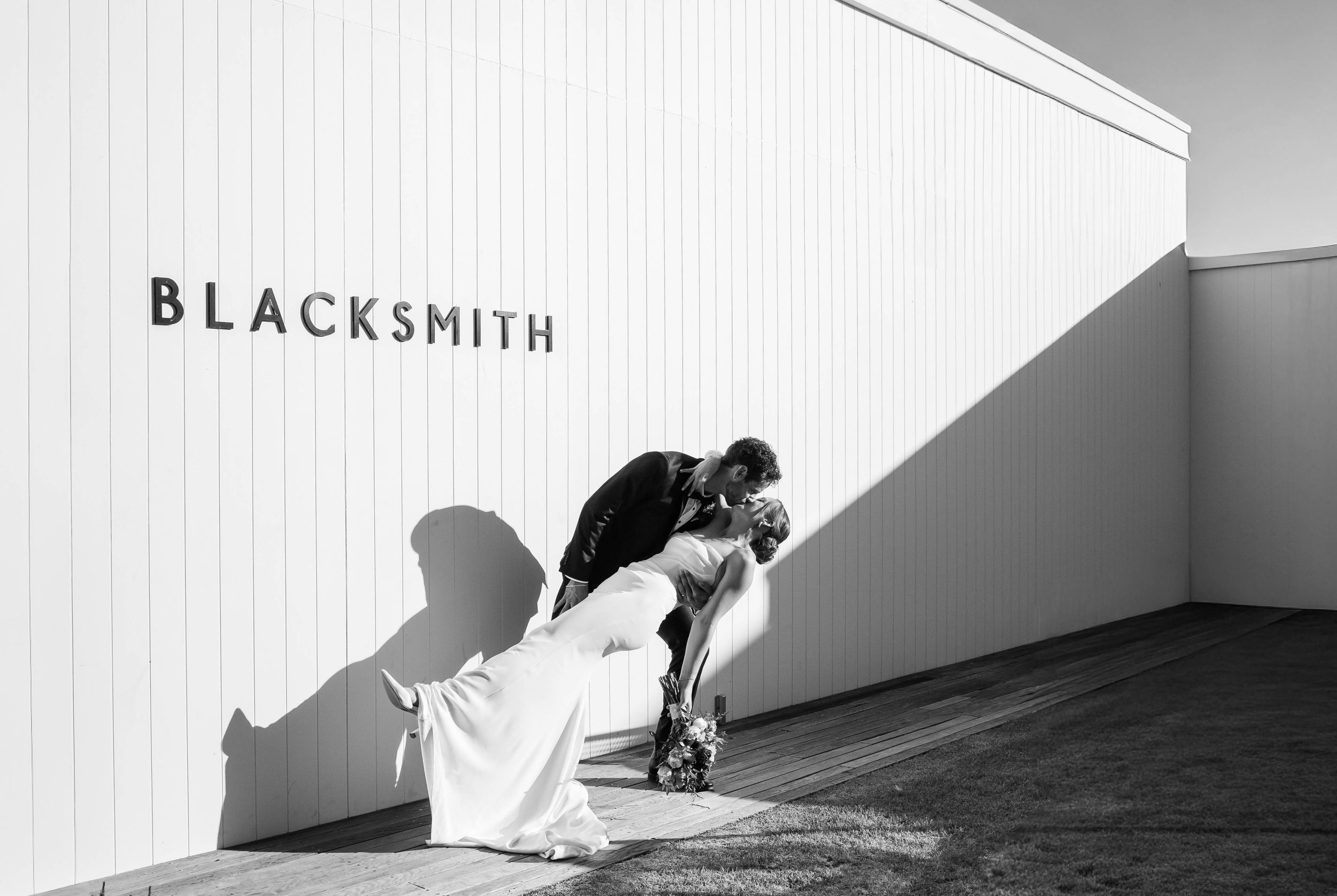 Modern minimalist architecture with white walls and a 'Blacksmith' sign creating dramatic shadows.