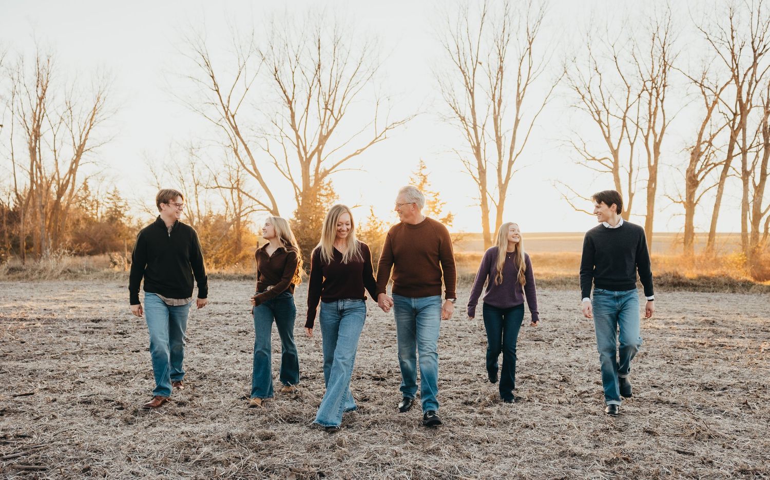 Family taking photos together in a blooming wildflower field at sunset.