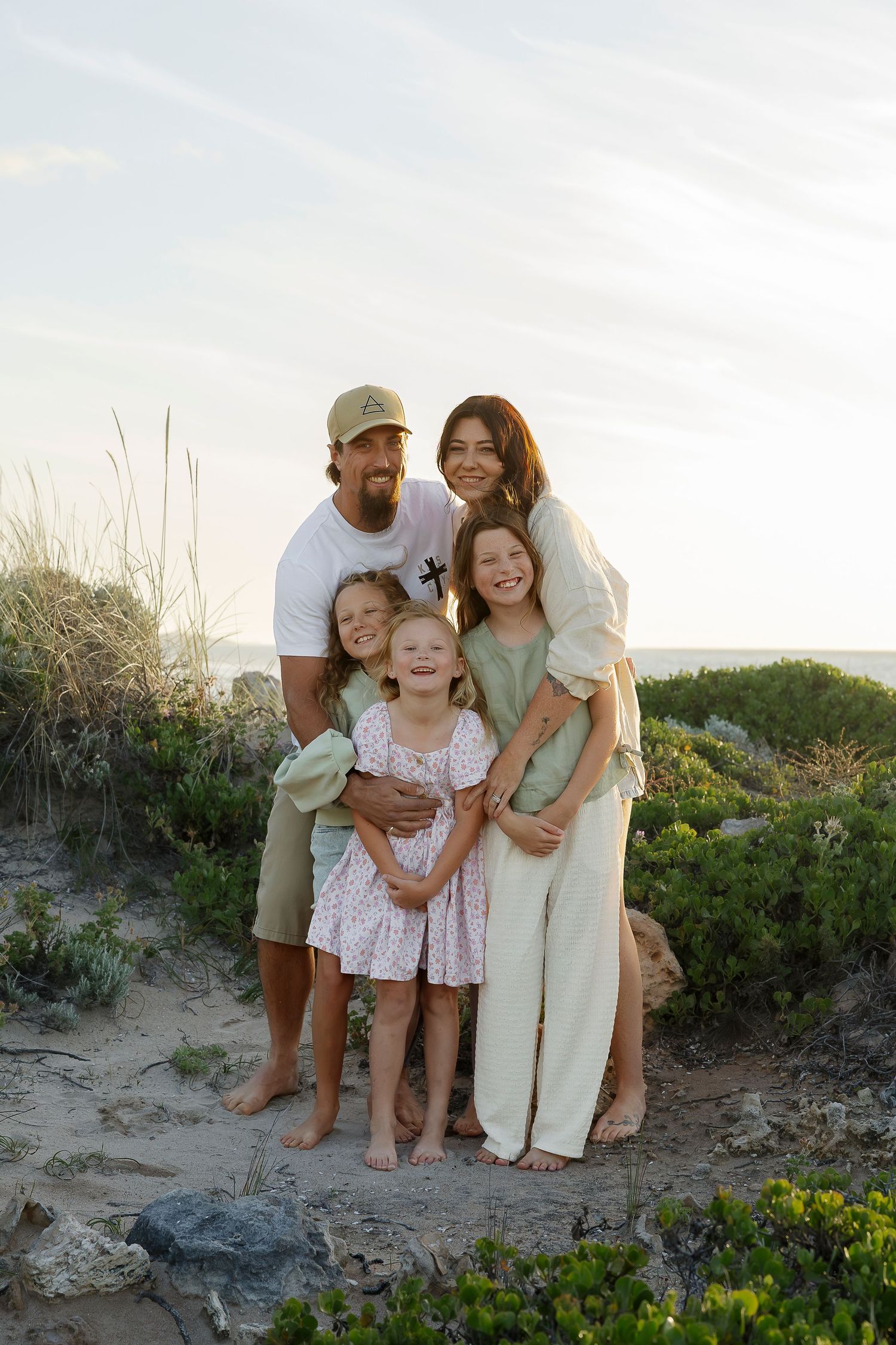 Family of five poses together among coastal dunes during a relaxed beach photoshoot at Halls Head Beach for a family session.
