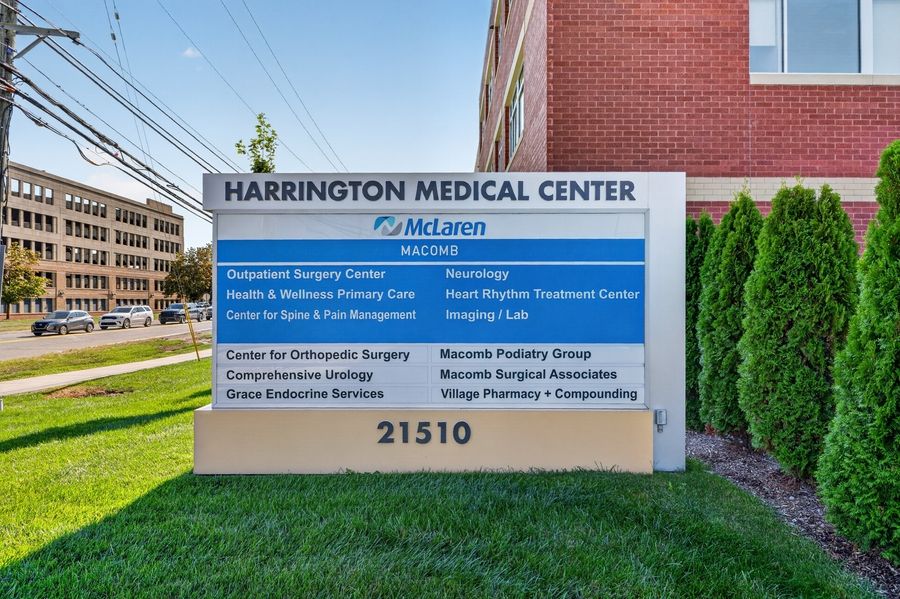Harrington Medical Center McLaren sign displaying multiple specialty services at 21510, with brick building in background.