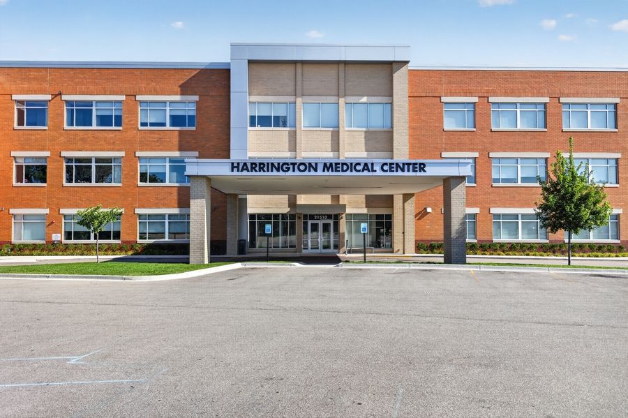 Harrington Medical Center exterior featuring modern brick building with glass entrance, clear blue sky, and empty parking lot.