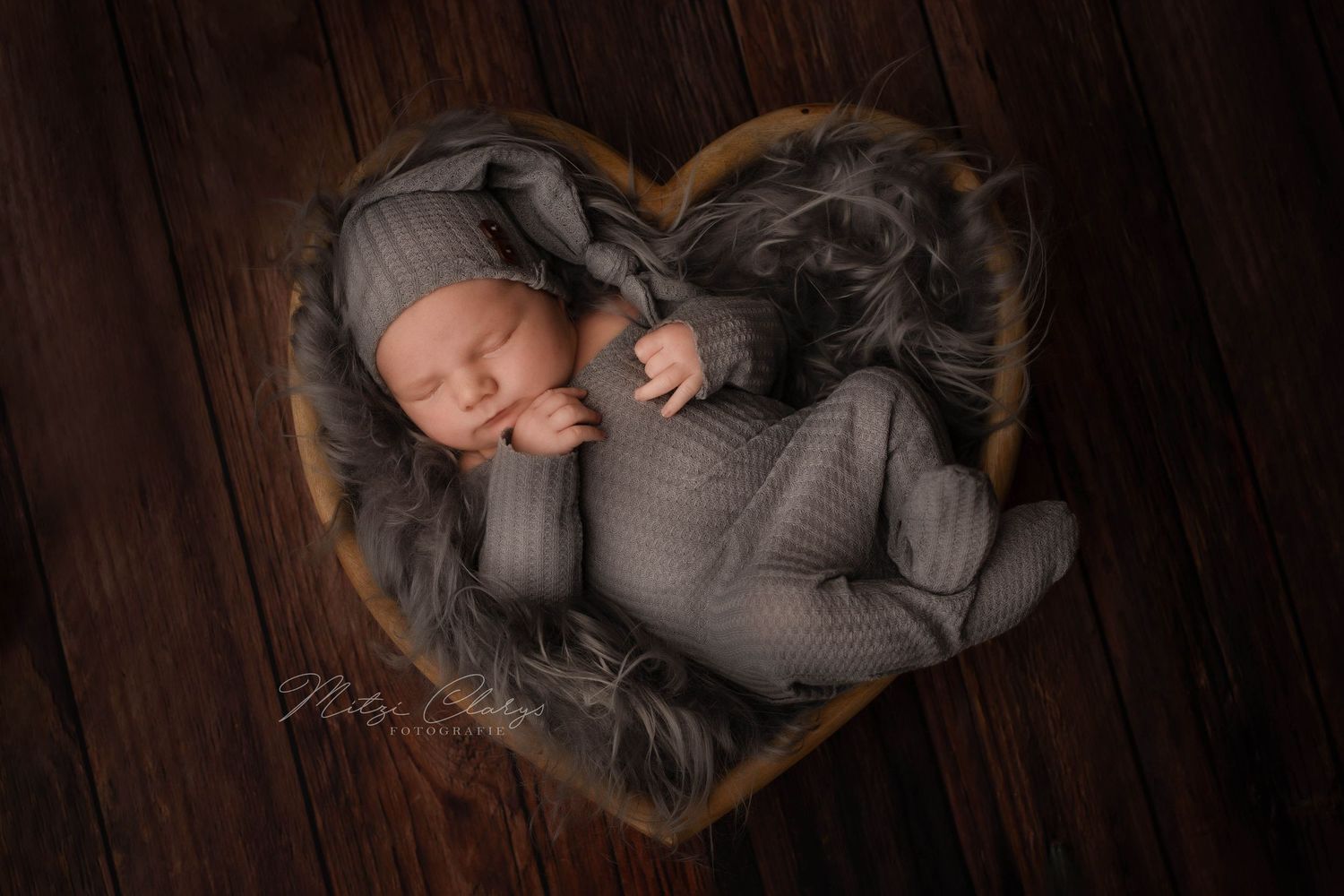 Newbornfotografie met pakje, mutsje, hartvormige schaal en accessoires in de studio