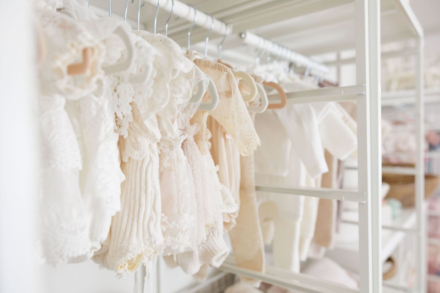 A boutique walk-in closet filled with pastel dresses on white racks, shelves, and a woven round rug on the floor.