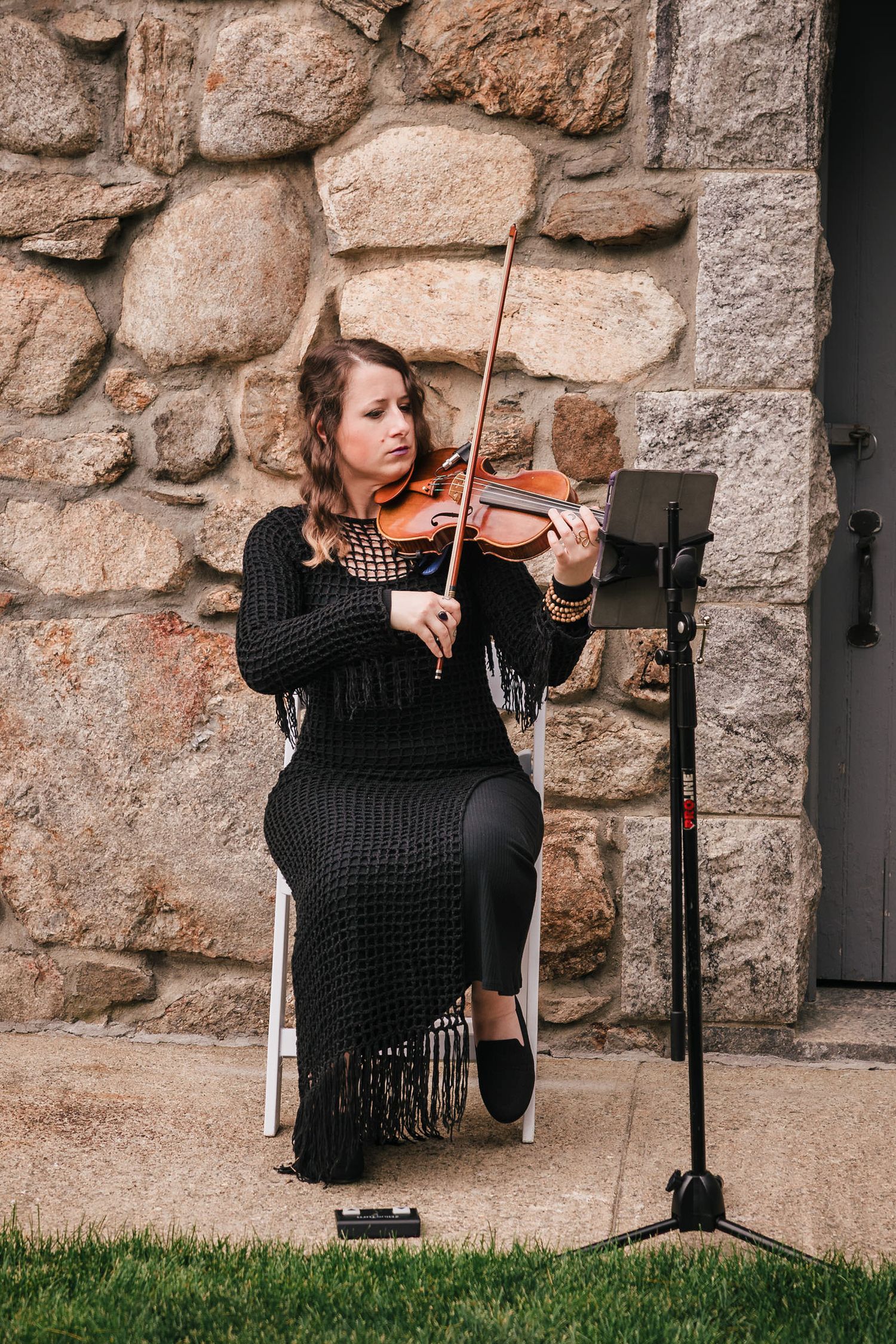 Violinist playing during the ceremony, seated against the stone wall at Searles Castle.