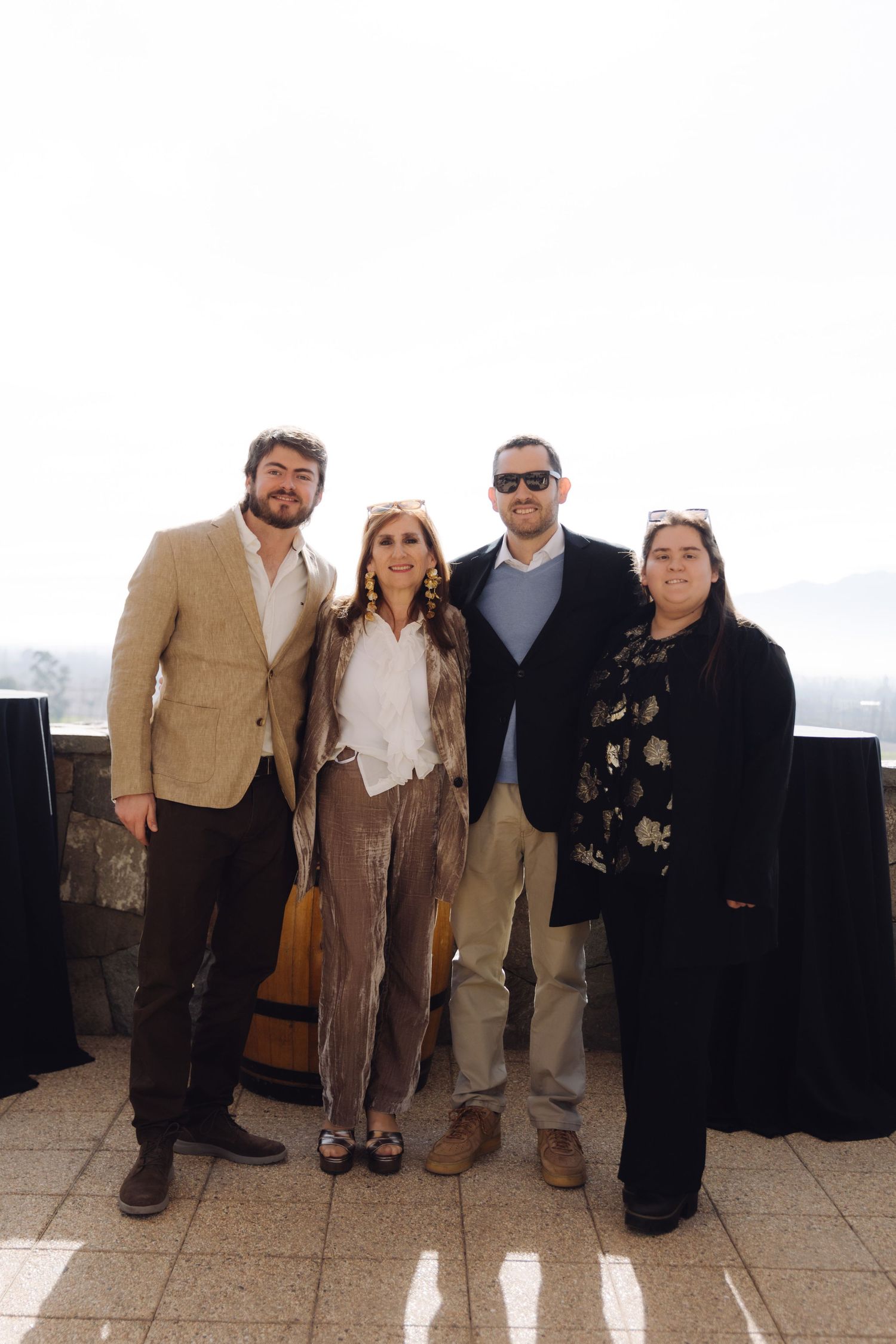 Four guests in smart casual attire posing together at outdoor rooftop event.