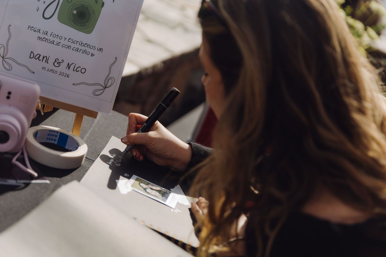 Woman with long hair signs guest book at elegant wedding reception table.