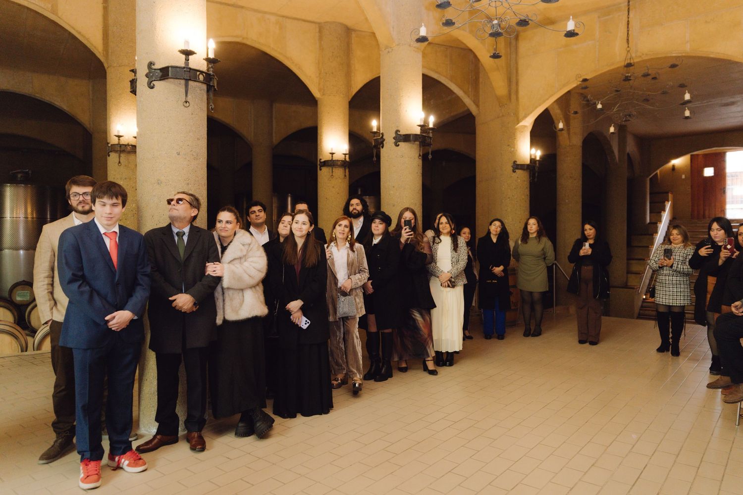 Wedding guests gathered in elegant arched winery hall during ceremony.