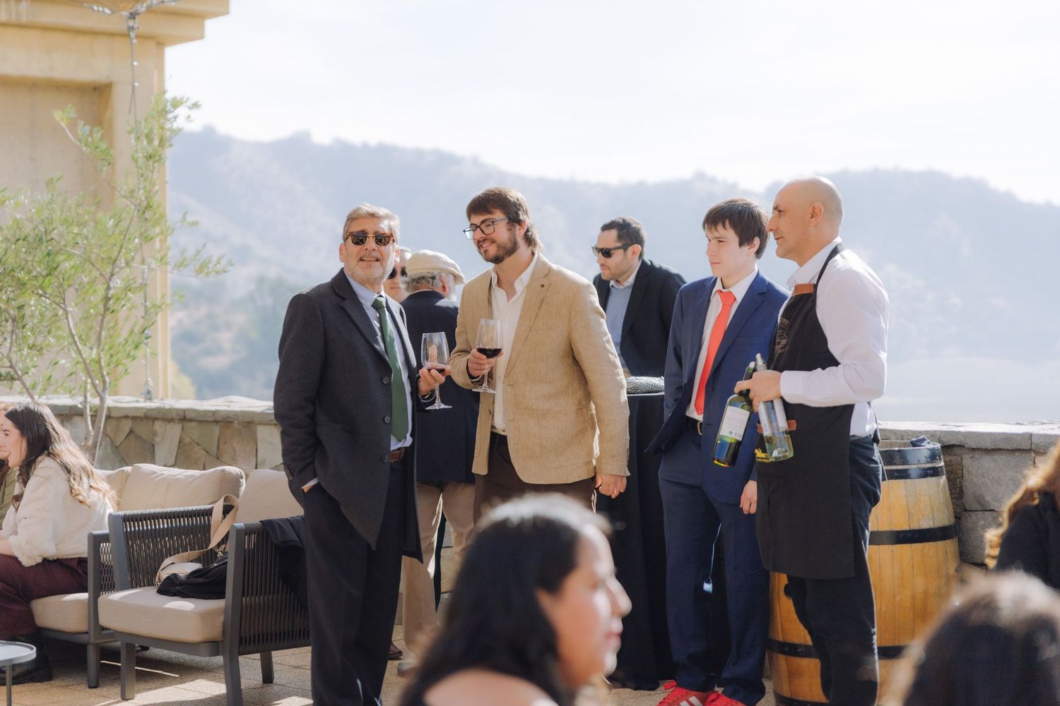 Guests mingle on an outdoor terrace with mountain views at a wedding cocktail hour.