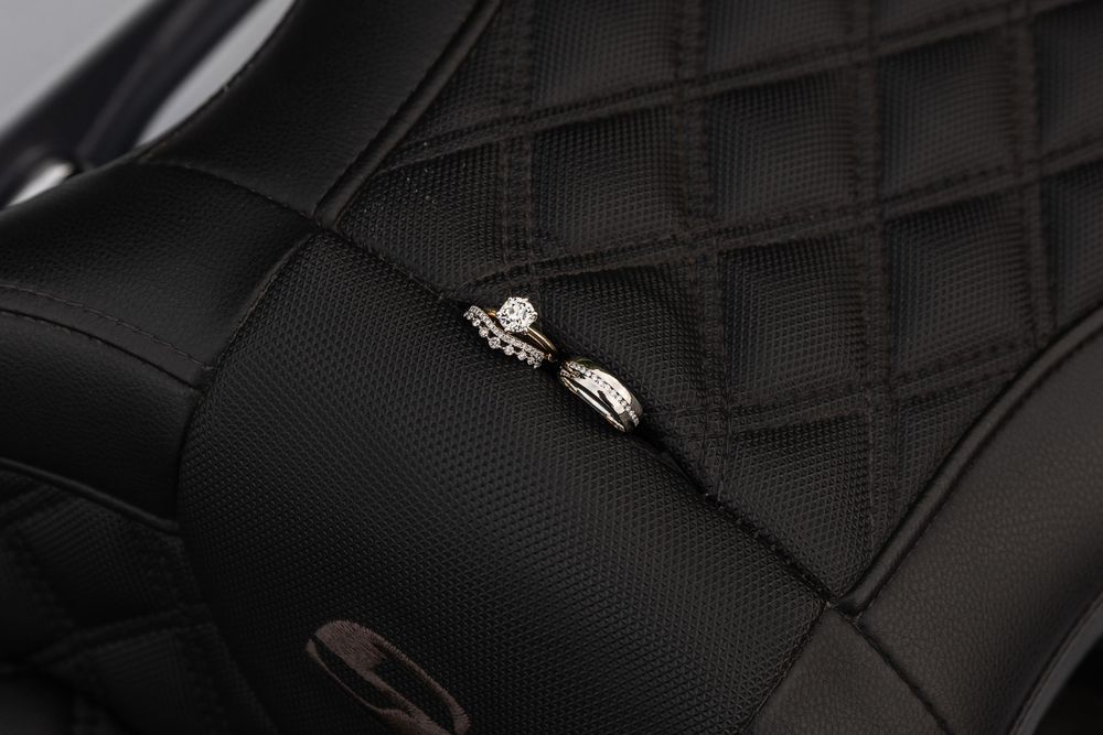 Close-up of wedding rings nested in a black quilted leather motorcycle seat.