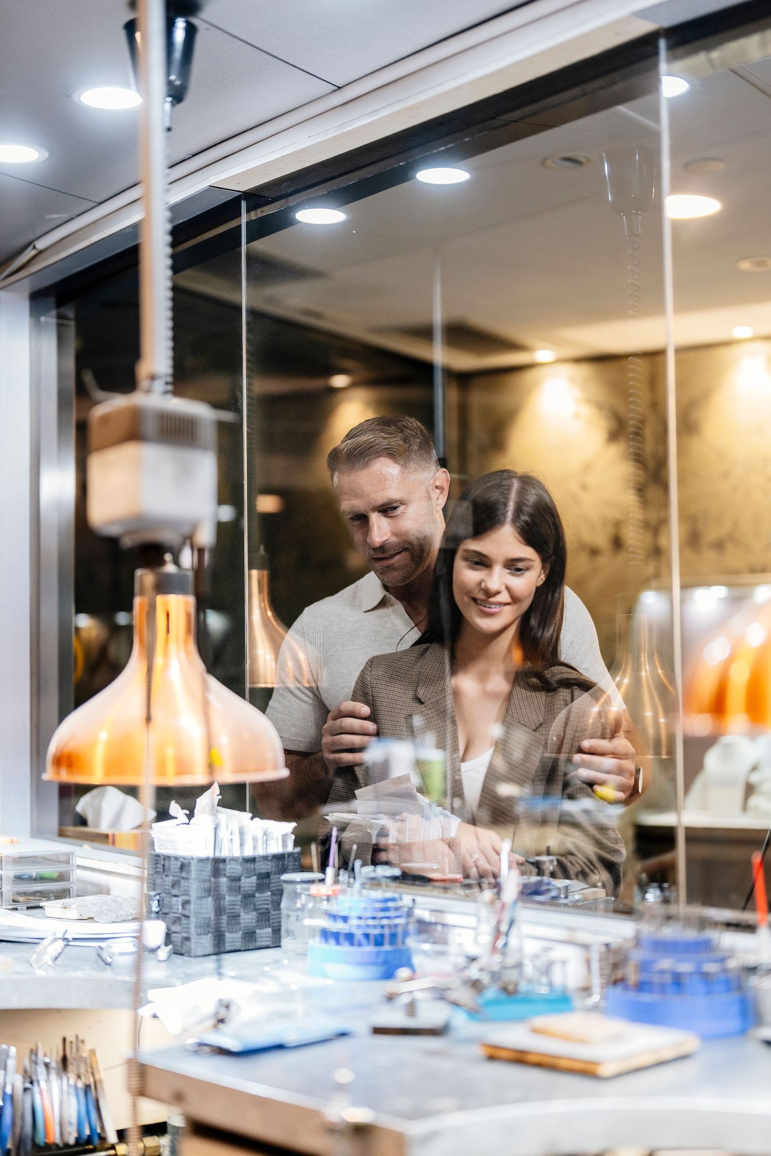 Couple smiling while browsing jewelry display cases in a modern boutique store with warm lighting brand films queensland