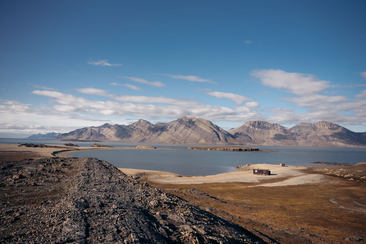 paysage d'un fjord du svalbard en été avec une baie et deux cabanes de scientifiques