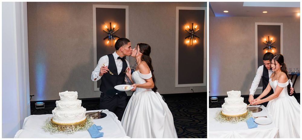 Bride and groom share a sweet kiss while cutting their elegant white wedding cake at their reception.
