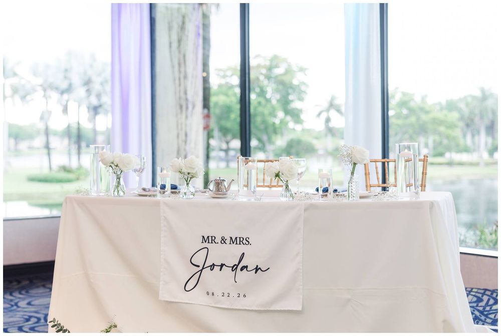 Mr. and Mrs. Jordan sweetheart table with white linen banner and floral centerpieces at wedding reception.