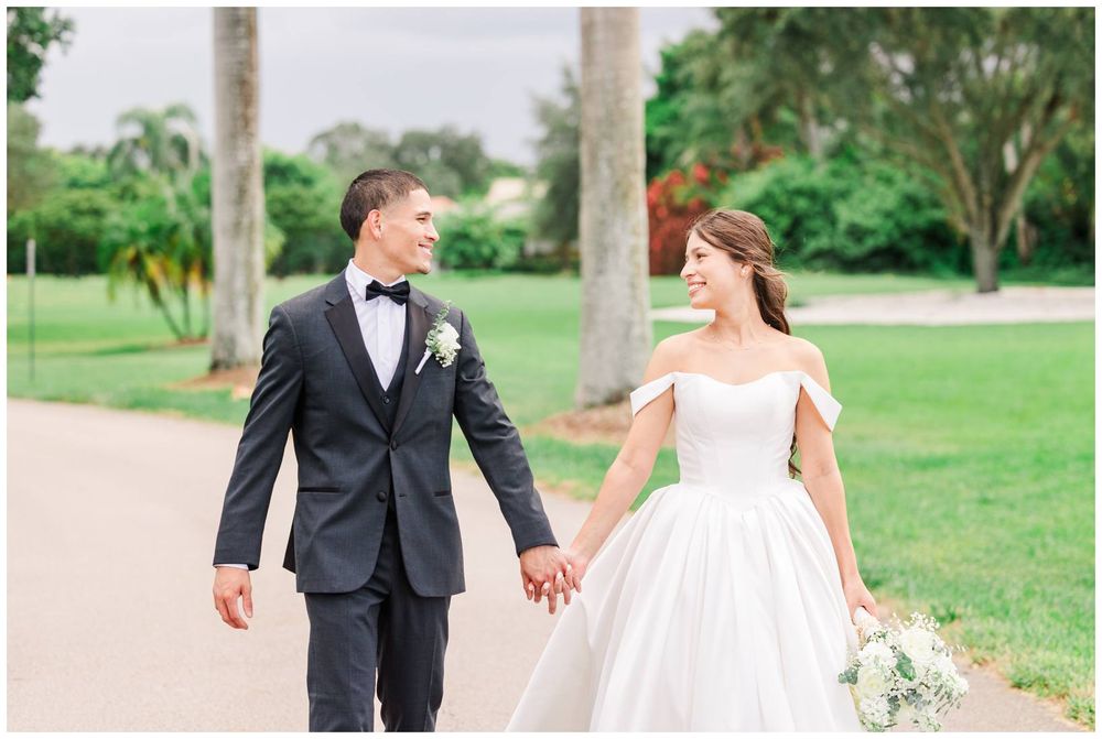 Bride and groom walk hand in hand along a palm tree-lined path on their wedding day.