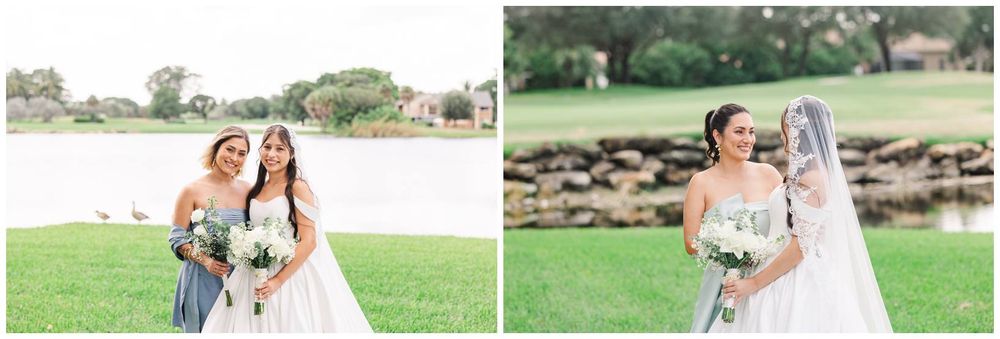 Bride and bridesmaid pose by a lakeside on a green lawn, both holding white bouquets in elegant white gowns.