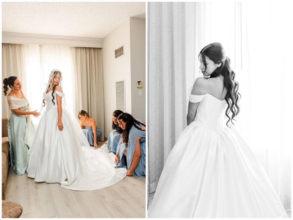 Bride in white ball gown being helped by bridesmaids in blue dresses during wedding preparations.